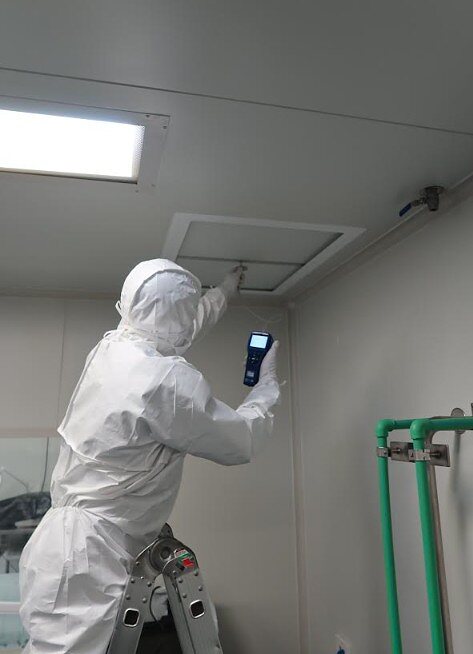 IAFS technician taking air flow readings at a ceiling HEPA filter