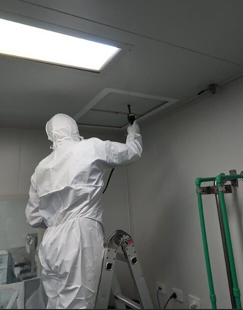 IAFS technician testing a ceiling air supply panel from a ladder